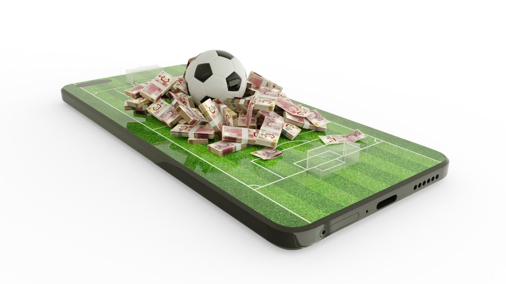 Football and British pound sterling notes on phone screen